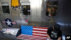 一位男士坐在北京某家出售美國名牌服裝的時尚精品店外繪有美國國旗圖案的長椅上看手機。（2019年5月13日）