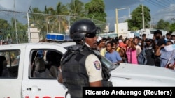 在海地首都太子港，海地國家警察守衛著美國大使館的入口。在總統莫伊斯遭暗殺身亡後，一些海地民眾聚集在美國大使館門口尋求庇護。（2021年7月9日）