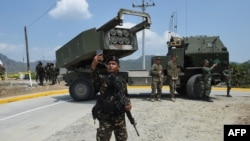 一名菲律宾士兵在参加美菲联合军演后在高机动多管火箭系统(HIMARS) 前用手机自拍。（2016年4月14日）