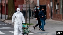 A woman wearing a hazmat suit and googles pulls her grocery cart in the streets in Queens, a borough of New York City, amid the coronavirus pandemic on April 20, 2020.