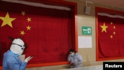 2020年2月27日，武汉一座体育馆改建的医院，一名医护人员试图安抚病患