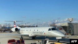 FILE - Baggage handler vehicles are seen near an American Eagle Embraer EMB 145 plane on the tarmac of Philadelphia International Airport, outside Philadephia, Pennsylvania, Jan. 8, 2020. 
