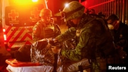 墨西哥消防人员在华雷斯城移民设施发生火灾后在现场救治伤员。（2023年3月28日）