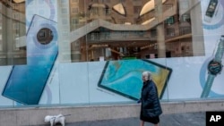 一女子牽一狗從華為在西班牙首都馬德里的一家商店外走過（2020年2月20日）。