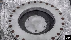 ​ຮູບນີ້ ທີ່​ສະ​ໜອງ​ໂດຍອ​ົງ​ການ​ນາ​ຊາ ເມື່ອ​ວັນ​ທີ 11 ຕຸ​ລາ 2023 ສະ​ແດງ​ໃຫ້​ເຫັນ​ຂ້າງນອກ ຂອງ​ເຄື່ອງ​ເກັບ​ຕົວ​ຢ່າງ ຝຸ່ນ​ແລະ​ກ້ອນ​ຫີນ Osiris-Rex ຈາກ​ດາວ​ເຄາະ​ນ້ອຍ ເບັນ​ນູ (Bennu). ຕົວ​ຢ່າງ​ສ່ວນ​ໃຫຍ່​ແມ່ນ​ຢູ່​ຂ້າງ​ໃນ. (NASA via AP)