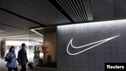 在中國北京的一個購物中心，人們走過體育用品零售商耐克公司的商店（2021年3月25日）。
