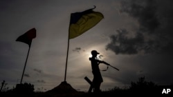 11歲的馬克西姆在烏克蘭哈爾科夫州的一條公路的自設檢查站上端著塑料玩具槍。(2022年7月20日)