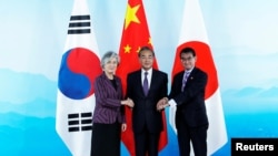 南韓外長康京和（左起）、中國外長王毅和日本外相河野太郎在北京舉行的中日韓三國外長會議上握手。 （2019年8月21日））