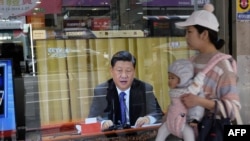 2019年1月2日，台灣新北市，一位母親帶著孩子經過一台電視，上面顯示中國領導人習近平就台灣問題發表講話。