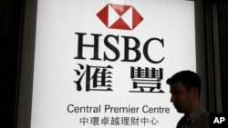 一名男子走過香港匯豐銀行一個支行的廣告燈箱。