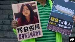 一名香港民主活動人士在中聯辦外手持上海維權人士、公民記者張展的照片。 （2020年12月28日）