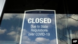 在馬薩諸塞州戴德姆的一個露天商場，一家商店的櫥窗上貼著一個關閉的告示（2020年4月22日）。