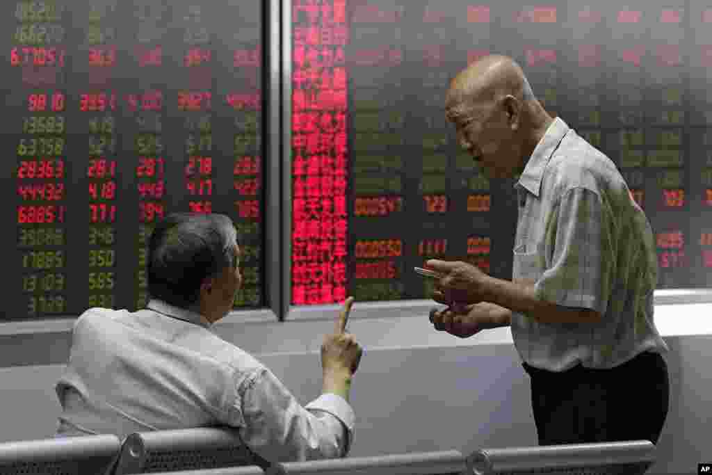 股民在北京一个经纪公司观看股票价格时聊天（2018年8月16日）。8月17日晚，中国证监会照例核发了IPO批文，批准两家公司融资10亿。有些业内人士称，中国股市恐慌蔓延，证监会仍照发IPO批文，是在落井下石。但是中国官媒说，中国经济稳中向好，上市公司业绩稳步增长，股市估值水平处于历史低位。