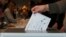 2024年10月8日立陶宛維爾紐斯一名選民在立陶宛大選提前投票期間將選票投入選票箱。