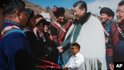 在中國西南部四川省成都市的一家酒店裡，一名男子拿著雨傘走過一張中國國家主席習近平會見少數民族的照片。（2020年9月9日）