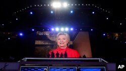 人在紐約的希拉里突然透過視像連線現身黨代會﹐說她的提名為那玻璃天花版衝出了最大的一道裂縫。