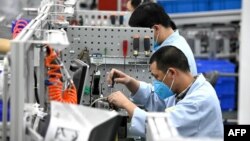 上海生產醫療設備的西門子工廠工人戴著口罩在生產線上工作。 （2020年2月24日）