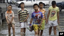 泰國小童在遭水掩的曼谷街頭過路﹐泰國政府已經準備排洪。