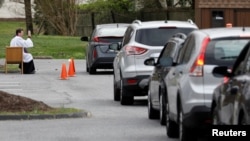 2020年3月21日斯科特·霍爾默神父坐在教堂停車場椅子上傾聽開車經過的教區居民懺悔