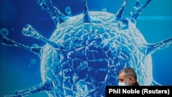 一名英國戴口罩路人經過當地科學中心的宣傳畫（照片來自路透社REUTERS/Phil Noble）