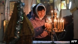 一名女子在烏克蘭哈爾科夫的一座教堂裡參加東正教聖誕節彌撒時點亮蠟燭。（2023年12月24日）