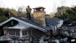 一名消防隊員站在加州蒙地西托一處被泥石流掩蓋的房屋頂上。（2018年1月10日）
