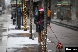 ຜູ້ຍິງຄົນນຶ່ງຍ່າງກັບໝາ ໃນເຂດແມນແຮັດຕັນ ໃນນະຄອນນິວຢອກ, ສະຫະລັດ, ວັນທີ 24 ທັນວາ, 2024. REUTERS/Marko Djurica