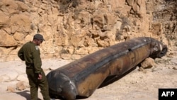 A member of the Israeli military personnel examines a part of an Iranian ballistic missile, recently located in an open area near the southern city of Arad, on April 24, 2024.