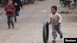 一个叙利亚小男孩在街上推着轮胎奔跑