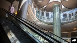 2022年5月21日，一名戴著口罩的女子在北京一家空空蕩蕩的商場裡的自動扶梯上。