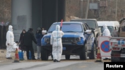 北京房山地區發現非洲豬瘟後，身穿防護服的防疫人員在通往出現疫情的村莊道路上設卡。（2018年11月23日） 