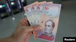 一名男子在委內瑞拉加拉加斯的銀行取款後，展示新的鈔票。 （2018年8月20日）。