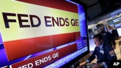 紐約證券交易所內的電視屏幕2014年10月29日消息顯示美國聯邦儲備局決定停止執行量化寬鬆政策 （AP）