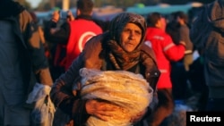 一名从反政府武装控制的阿勒颇东城区转移出来的平民抱着大饼和其他人一道抵达叙利亚反政府武装控制的拉西迪恩镇。（2016年12月15日）
