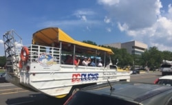Tourists take photos of the U.S. Capitol (not seen) from a tour boat-like bus on a hot day in Washington, DC. (Photo by Diaa Bekheet)