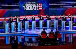 FILE - Democratic presidential candidates raise their hands during the Democratic primary debate at the Adrienne Arsht Center for the Performing Arts in Miami, Florida, June 27, 2019.
