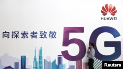 一名男子走過在北京舉辦的中國國際信息通信展覽會的一塊華為公司5G技術廣告牌。（2018年9月26日） 