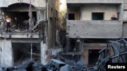 2024年12月13日，巴勒斯坦人在以色列袭击加沙地带中部努塞拉特难民营现场勘察损坏的情况。