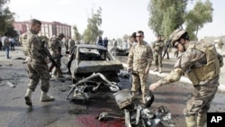 伊拉克安全部队士兵4月19日在基尔库克检查血迹斑斑的汽车炸弹爆炸现场