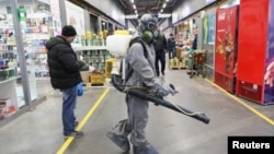 在俄羅斯首都莫斯科，一名身著防護裝備的人在噴灑消毒劑。（2020年4月9日）