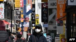 一位戴口罩的南韓女性走在首爾購物區街頭。