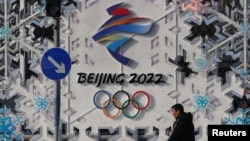北京街头一名男子走过一幅北京冬奥会的宣传画前。（2022年1月25日）