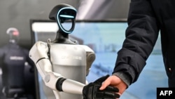 2025年2月21日，在上海人工智能產業協會組織的全球開發者先鋒大會上，一名男子與宇樹科技的一款人形機械人握手。