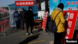 北京市民在进入一个市场前用手机刷健康码。（2021年1月11日）